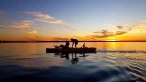 Silhouette kids on kayak in the sunset,